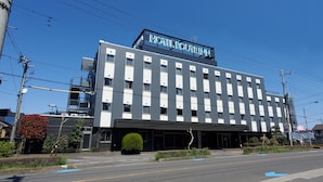Il s’agit d’un bâtiment d’hôtel moderne, sur lequel on peut lire l’inscription « HOTEL ROUTEINN ». Il présente une structure à plusieurs étages, une façade plate, de nombreuses fenêtres et un parking situé à l’avant.