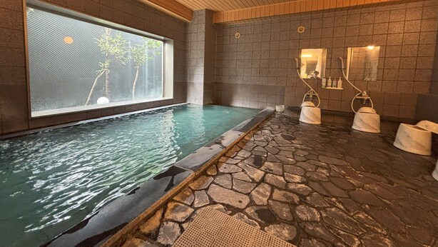 Un espace spa doté d’un sol carrelé en pierre, d’une grande fenêtre et d’une petite piscine.