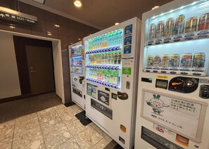 A row of vending machines in a hallway with a tiled floor and a door labeled "101-106". - Hotel Route Inn Ageo (Ageo)