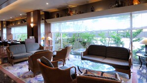A spacious lobby with a large window, wicker furniture, and a glass coffee table. - Kanazawa Manten Hotel Ekimae (Kanazawa)