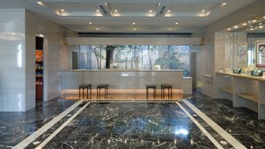 A modern lobby with a marble floor, a reception desk, and a view of trees through large windows. - Kanazawa Manten Hotel Ekimae (Kanazawa)