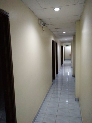 A long, narrow hallway with white walls and a tiled floor, leading to a door labeled "KELUAR". - Zass Hotel (Kuala Lumpur)