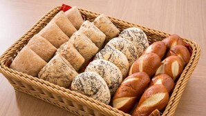 Una cesta con diferentes tipos de pan, incluyendo barras y bollos.