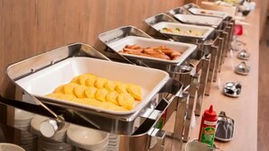 Una barra de buffet con distintos alimentos en bandejas de metal.