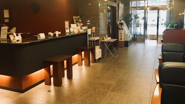 Zona de recepción con mostrador, asientos y un cartel que indica un restaurante.