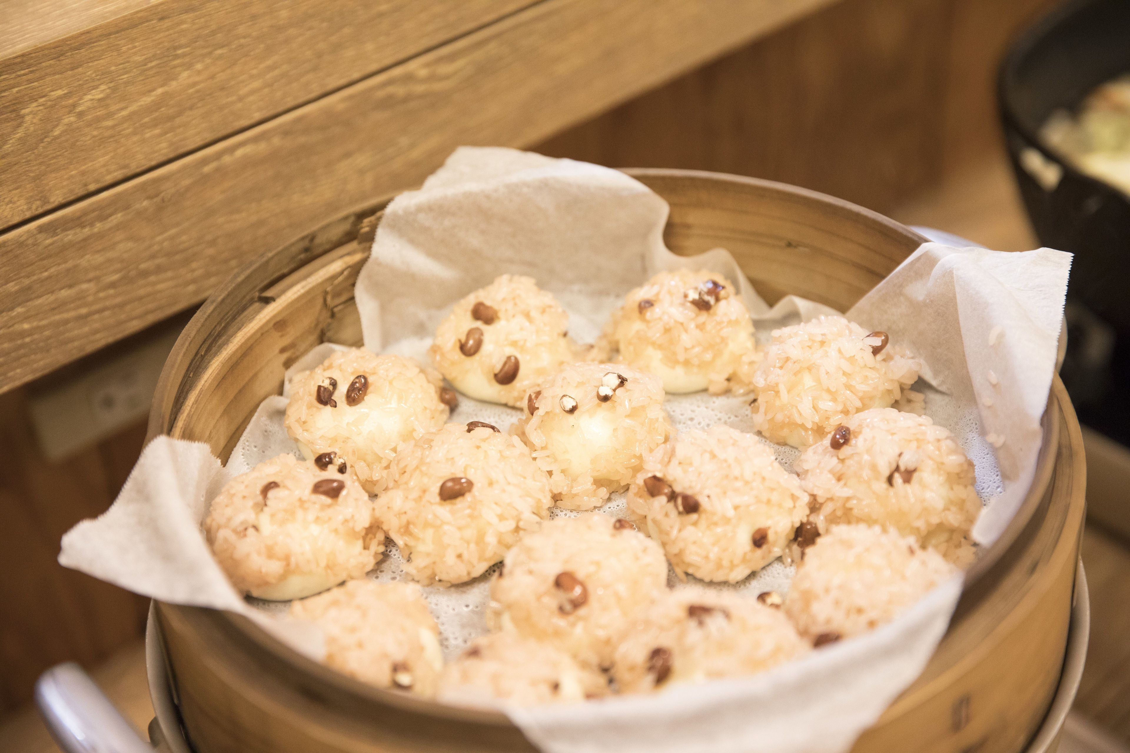 A steamer basket with steamed buns and beans.