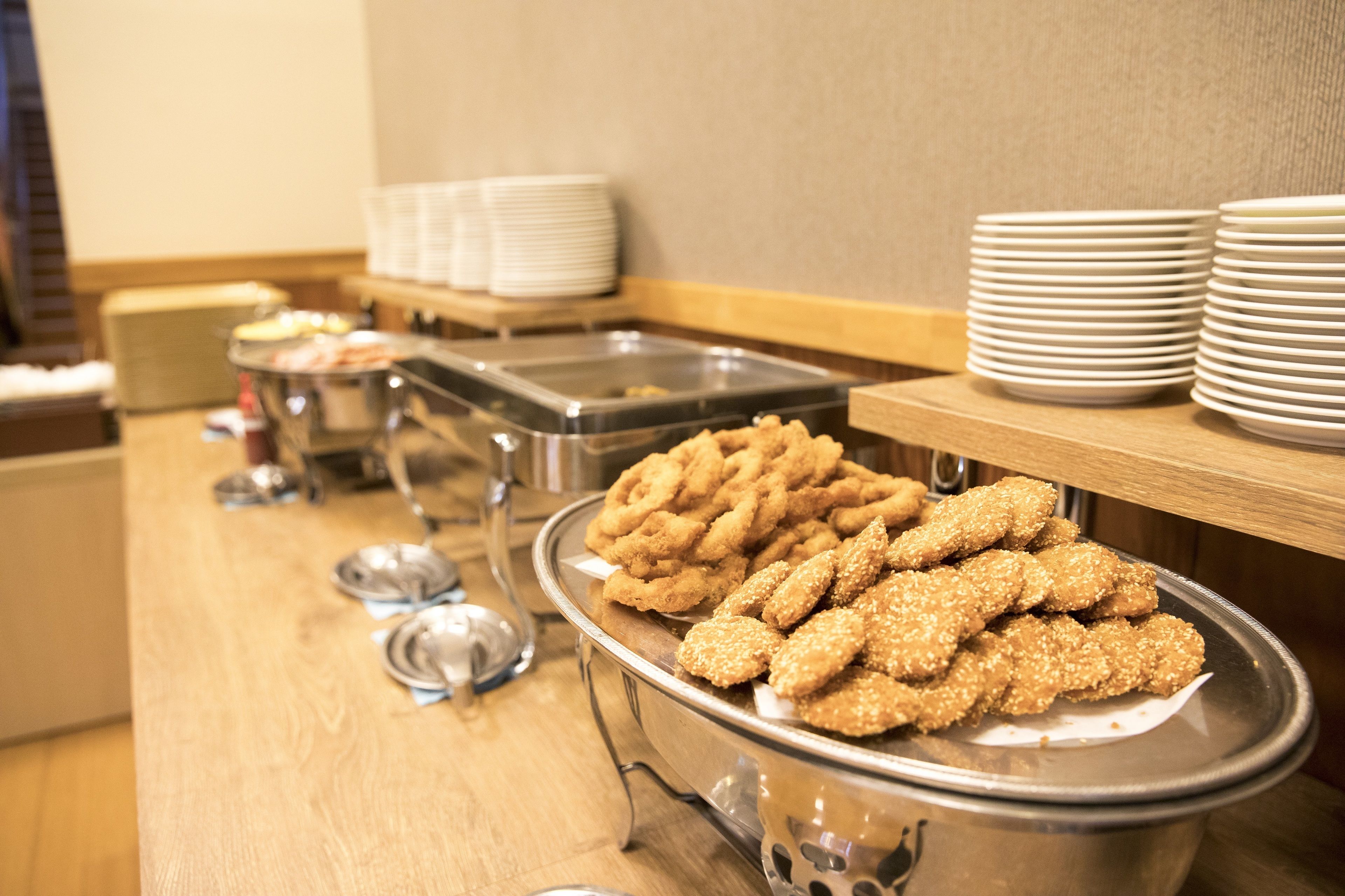 A buffet setup with various food items and stacked plates.