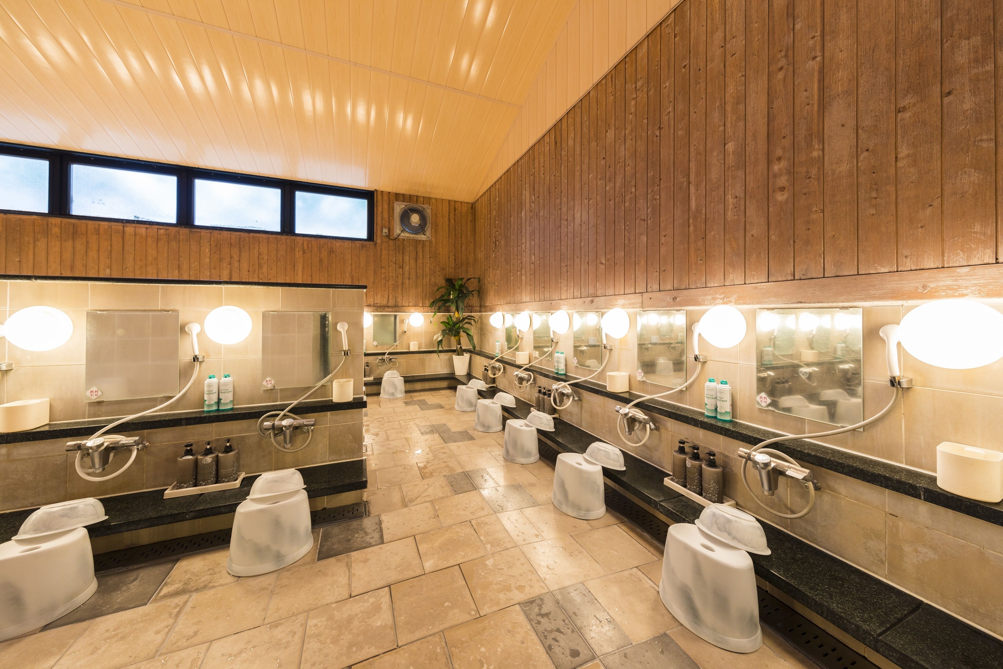 Baño público con varios lavamanos, espejos e iluminación.