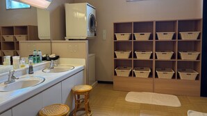 Un baño con lavadora, dos lavamanos, cestas de mimbre y una ventana.