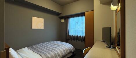 Une chambre d’hôtel comprenant un lit, un bureau avec un téléphone, un miroir, une fenêtre avec des rideaux et une œuvre d’art accrochée au mur.