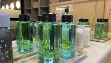 A display of green bottles on a marble countertop, likely containing personal care products.