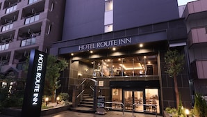 Exterior del Hotel Route Inn, con un letrero, una escalera y una entrada bien iluminada.