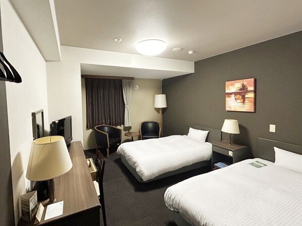 A hotel room with two beds, a desk, a chair, a TV, and a painting on the wall. - Hotel Route-Inn Itoigawa (Itoigawa)