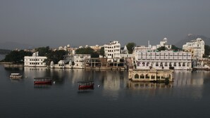 A riverside view of a historic city with white buildings and a traditional boat docked in the water.