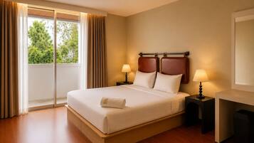 A hotel room with a large bed, two bedside tables with lamps, a window with curtains, and a view of greenery outside.