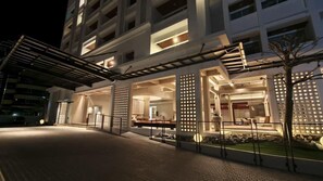 A modern hotel entrance with a covered walkway, outdoor seating area, and a well-lit facade. - Blanco Apartment Hotel (Bintulu)