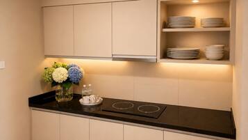 A kitchen with a black countertop, white cabinets, and a built-in shelf with plates.