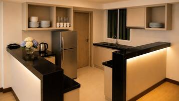 A compact kitchen with a built-in refrigerator, a sink, and a countertop with a vase of flowers.