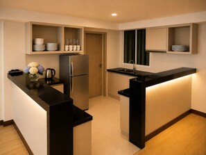 Eine kleine Küche mit integriertem Kühlschrank, einer Spüle und einer Arbeitsplatte mit einer Blumenvase.