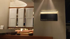 A modern interior with a reception desk, a wall-mounted sign reading "BLANCO", and a ceiling with linear light fixtures. - Blanco Apartment Hotel (Bintulu)