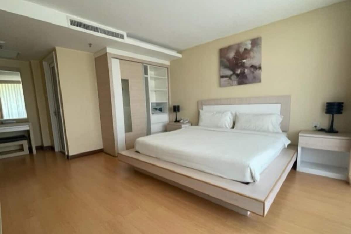 Une chambre à coucher moderne avec un grand lit, une armoire, un bureau et une table de chevet.
