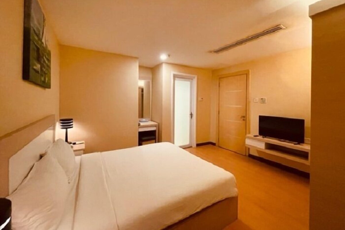 Ein Hotelzimmer mit Bett, Fernseher, Schreibtisch und Kleiderschrank.