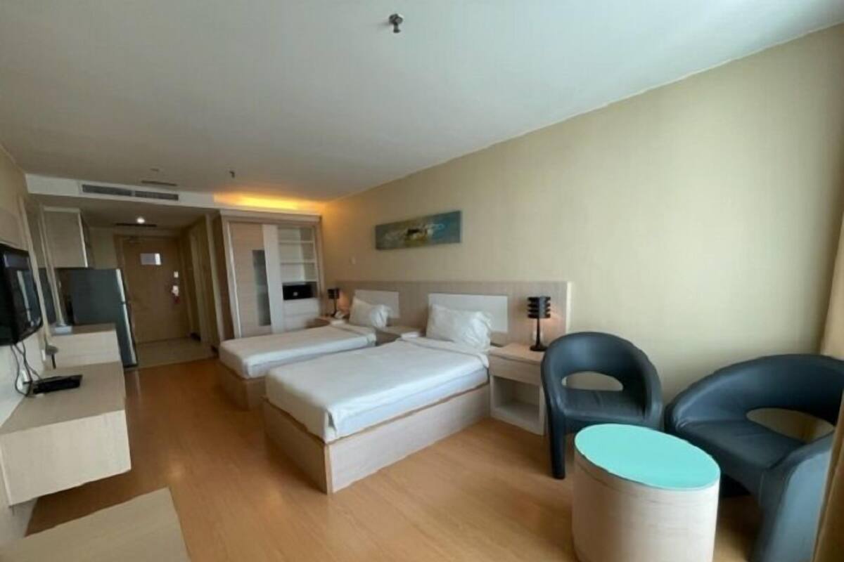 Une chambre d’hôtel avec deux lits, un bureau avec un ordinateur, une chaise et une petite table.