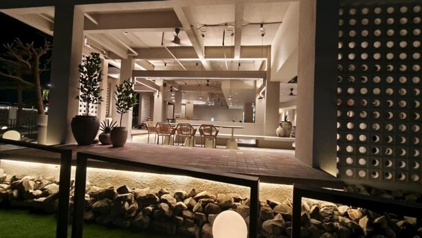 An indoor space with a modern design, featuring a central seating area with chairs and a table, surrounded by potted plants and a stone wall. - Blanco Apartment Hotel (Bintulu)
