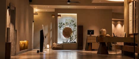 A modern interior with a central water feature, a ceiling fan, and a reception desk.