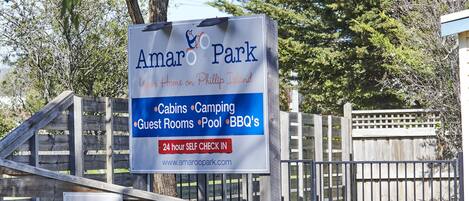 Señal de Amar Park con servicios como cabañas, camping, habitaciones de huéspedes, piscina y barbacoas.
