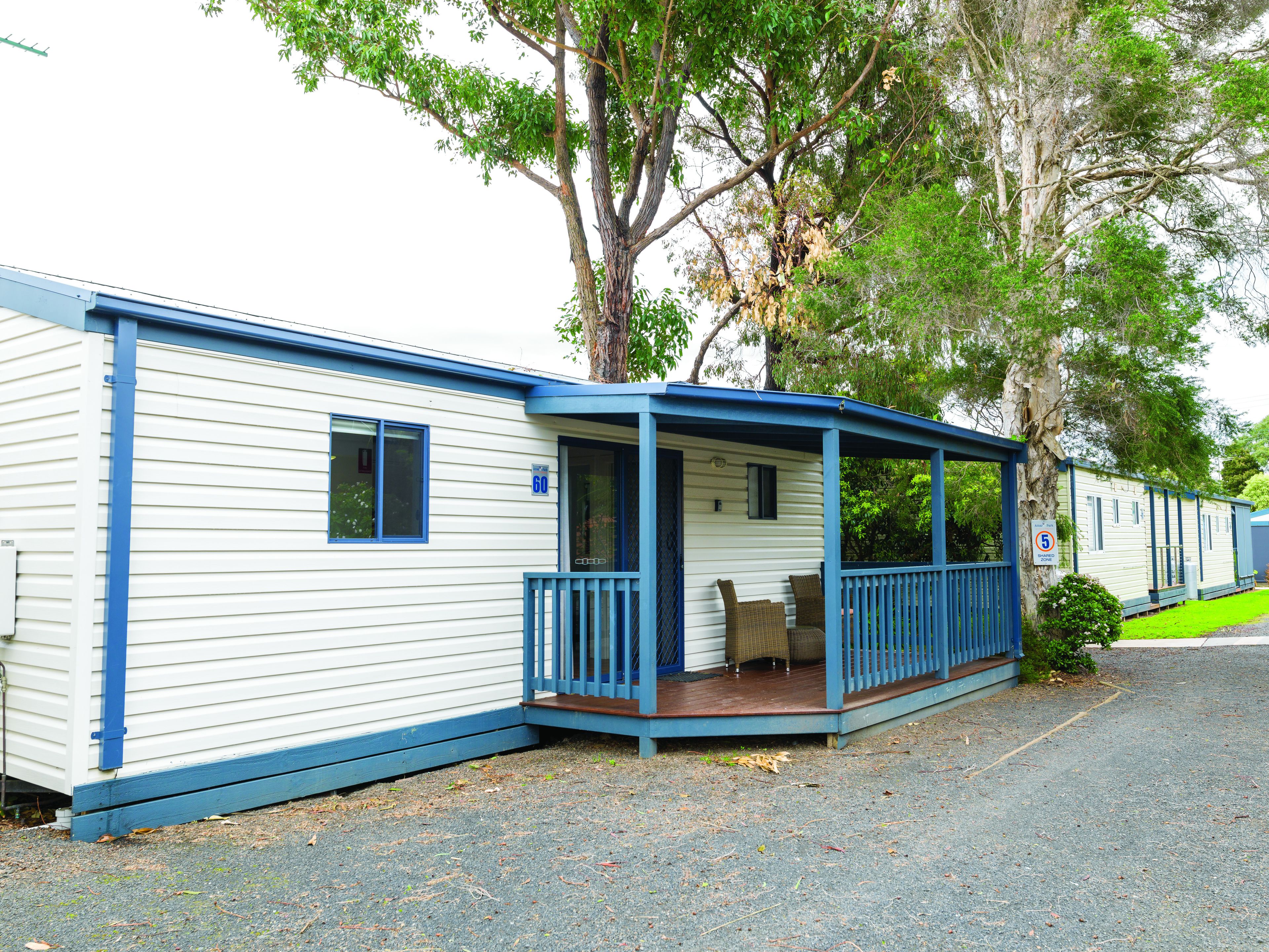 A row of mobile homes with a covered porch and a small garden area.