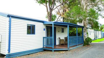 A row of mobile homes with a covered porch and a small garden area.