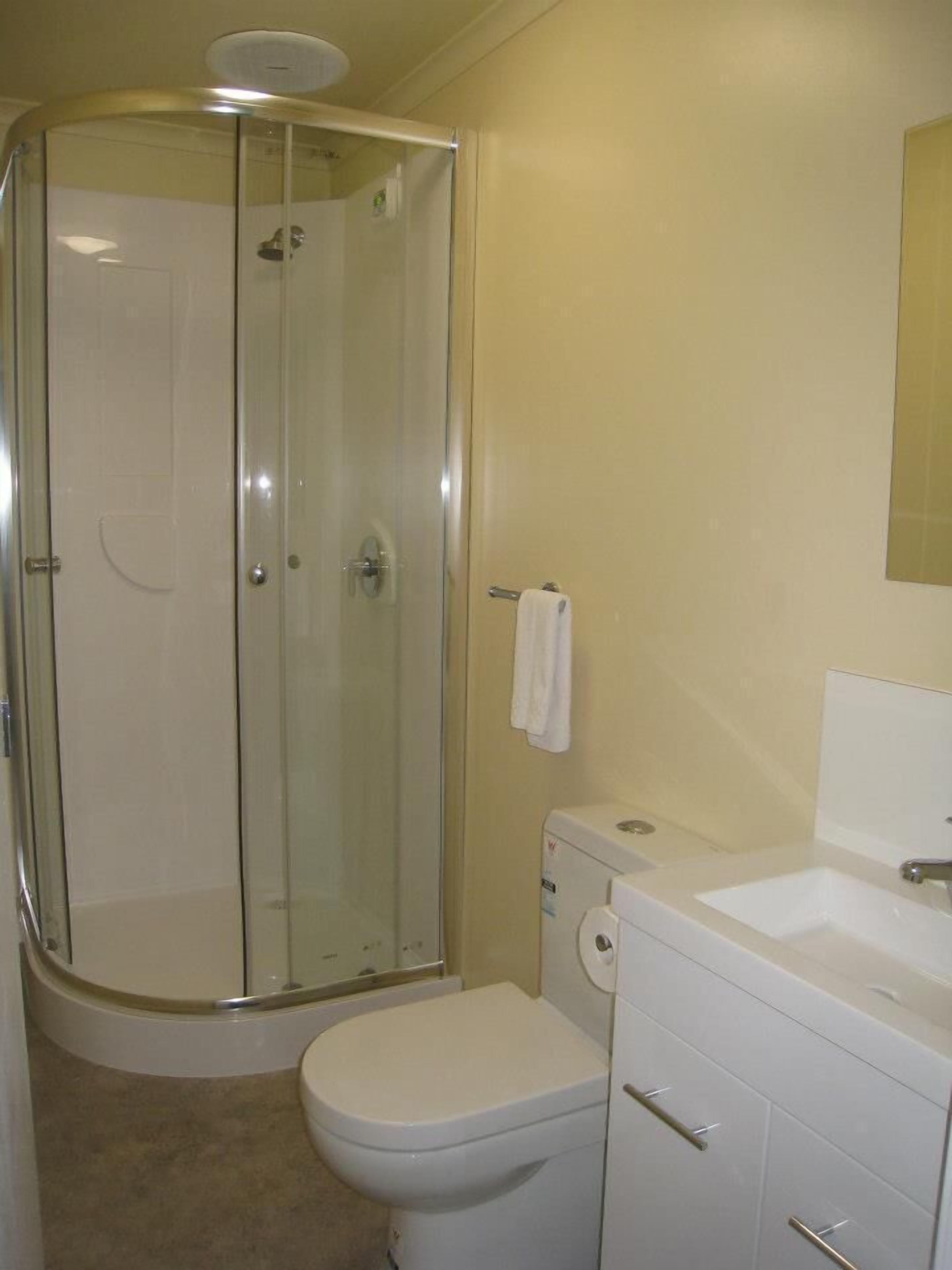 A bathroom with a glass-enclosed shower, a toilet, and a sink.