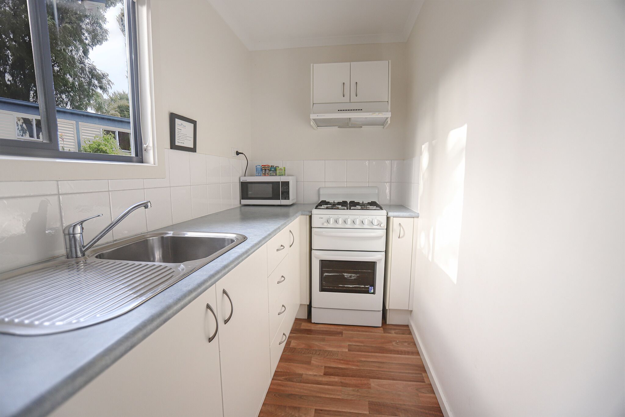 A compact kitchen with a stainless steel sink, a microwave, and a gas stove.