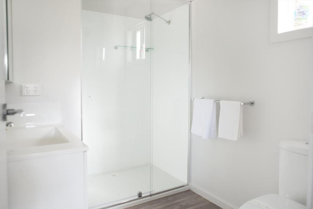 A modern bathroom with a glass shower enclosure, a white sink, and a toilet.