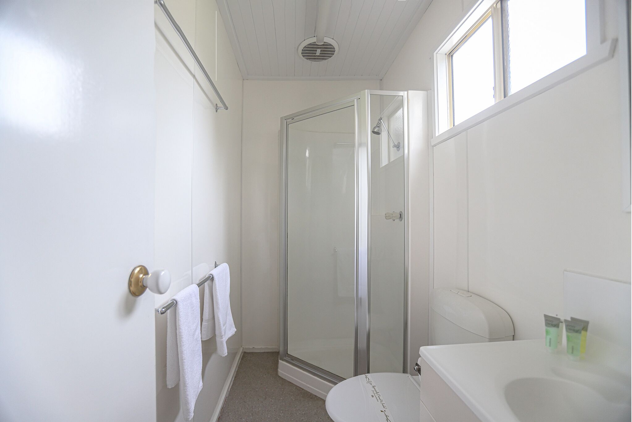 A bathroom with a glass-enclosed shower, a toilet, and a sink.