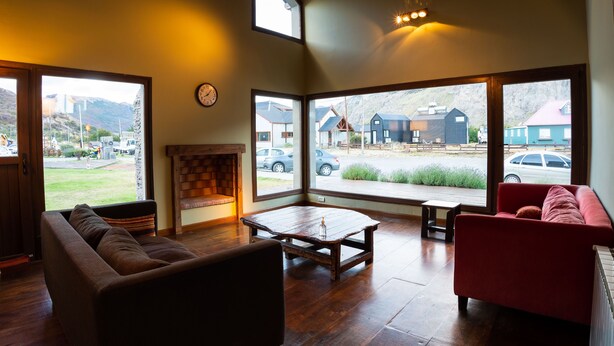 A cozy living room with a fireplace, a red couch, and a wooden coffee table. - Hotel Poincenot (El Chalten)