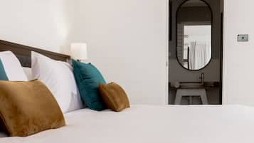 A neatly made bed with white and brown bedding, a wooden headboard, and a framed picture on the wall.