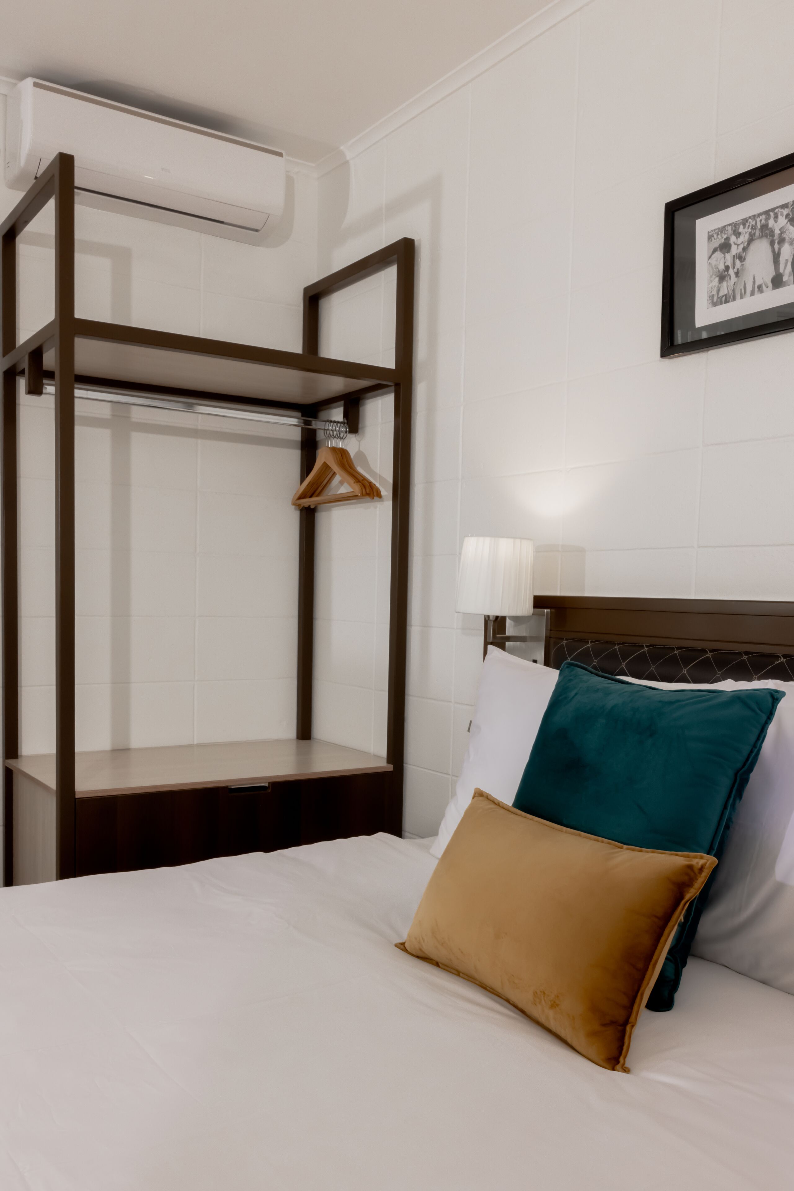 Habitación de hotel con literas, un perchero, una lámpara de noche y un cuadro en la pared.