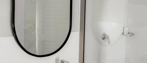 A bathroom with a white sink, a mirror, and a shower.