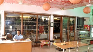 Een restaurant met een toonbank, stoelen en een vitrine vol producten.