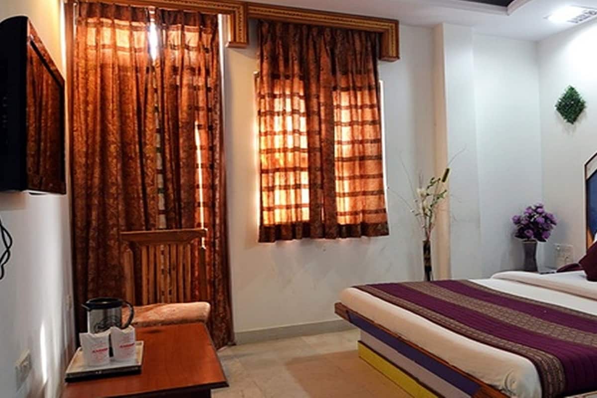 Une chambre à coucher avec un lit, des rideaux, une table de chevet et un climatiseur fixé au mur.