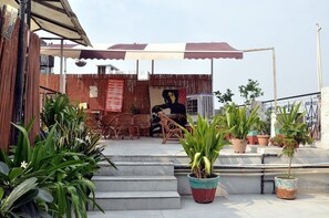 A rooftop terrace with outdoor seating, potted plants, and a mural. - Anoop Hotel (New Delhi)