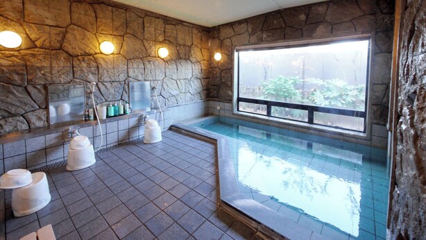 A stone-walled bathroom with a large window, a bathtub, and a shower area. - Hotel Route-Inn Court Minami Matsumoto (Matsumoto)