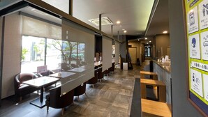 Un restaurante moderno con una barra alargada, cabinas individuales y vista a la calle.