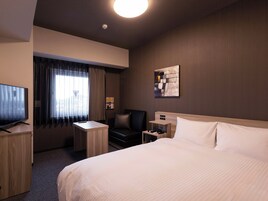 A hotel room with a bed, a desk, a chair, a TV, a nightstand, a lamp, a painting, and a window with curtains.
