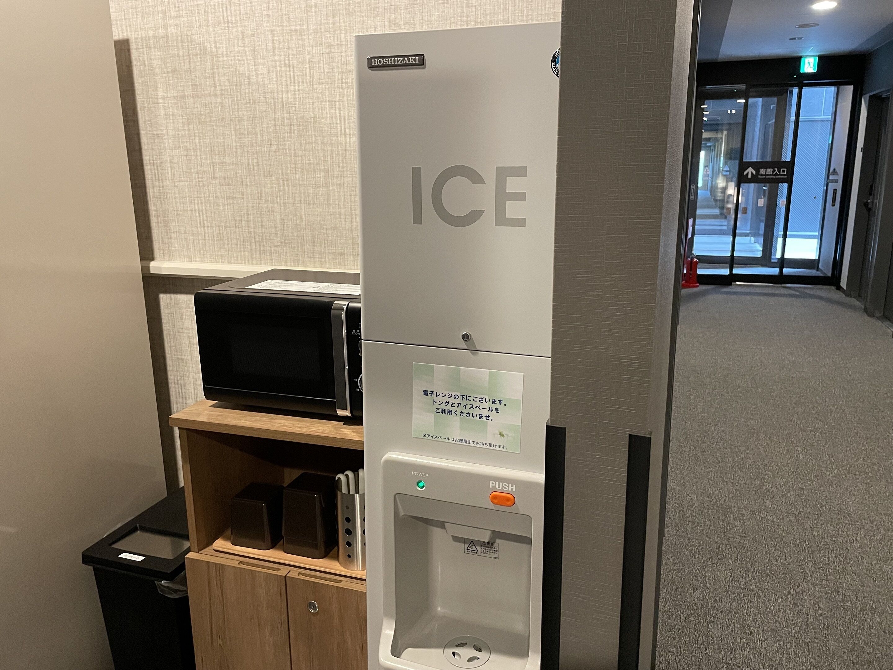 A hotel entrance with a reception desk, a vending machine, and a water dispenser.