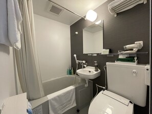 A bathroom with a bathtub, sink, and toilet. There is a towel hanging on the wall, and a hairdryer on a shelf. - Hotel Route-Inn Saku Minami Inter (Saku)