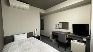 Una habitación de hotel con cama, escritorio, televisor y aire acondicionado.