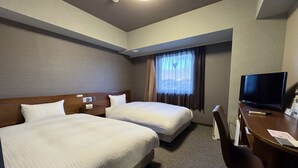 Une chambre d’hôtel avec deux lits, un bureau avec une télévision et une fenêtre avec des rideaux.